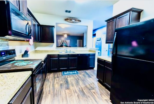 kitchen featuring sink, tasteful backsplash, light hardwood / wood-style flooring, dark brown cabinets, and black appliances