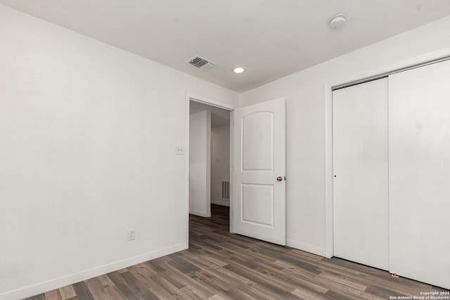 unfurnished bedroom with a closet and dark wood-type flooring