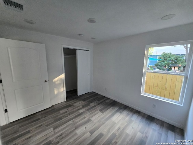 unfurnished bedroom featuring a closet, dark wood-type flooring, and a textured ceiling