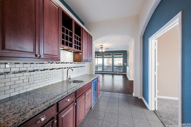 kitchen featuring backsplash, light stone counters, stainless steel dishwasher, and sink