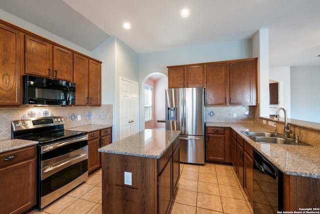 kitchen with a center island, black appliances, sink, decorative backsplash, and light stone countertops