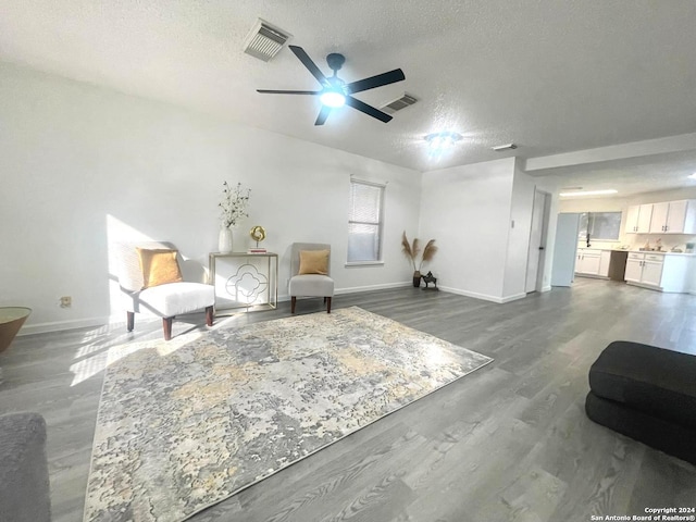 sitting room featuring hardwood / wood-style floors, ceiling fan, and a textured ceiling