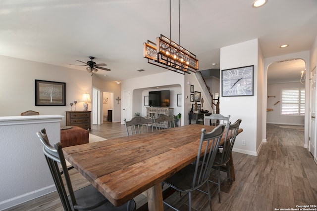 dining room with ceiling fan with notable chandelier and dark hardwood / wood-style flooring