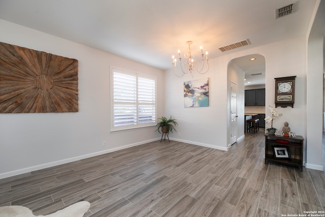 empty room with dark hardwood / wood-style flooring and a chandelier