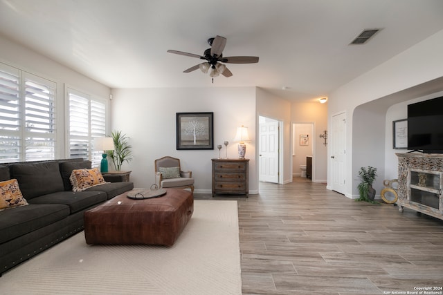 living room with ceiling fan, light wood-type flooring, and a fireplace