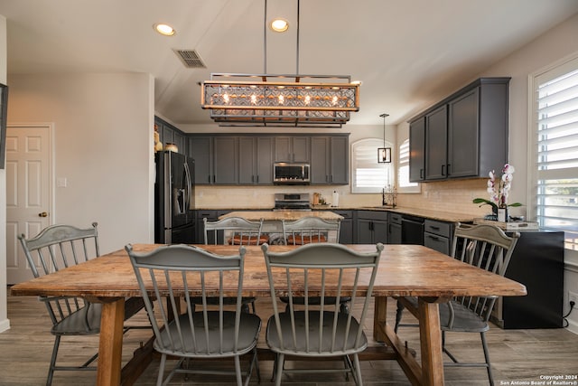 kitchen featuring decorative backsplash, stainless steel appliances, pendant lighting, light hardwood / wood-style flooring, and gray cabinets