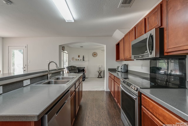 kitchen featuring a textured ceiling, stainless steel appliances, dark wood-type flooring, sink, and a center island