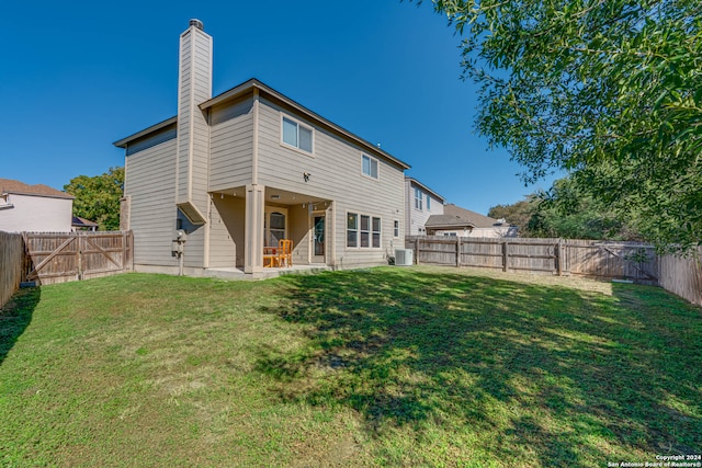 rear view of property featuring a lawn, cooling unit, and a patio