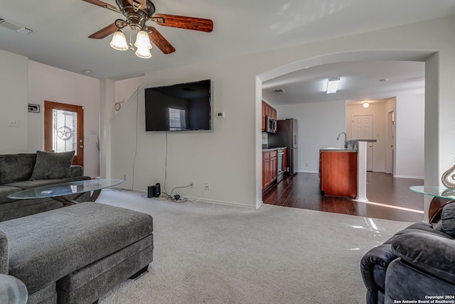 living room featuring dark hardwood / wood-style flooring, ceiling fan, and sink