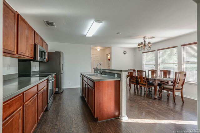 kitchen with sink, stainless steel appliances, dark hardwood / wood-style flooring, an island with sink, and a chandelier