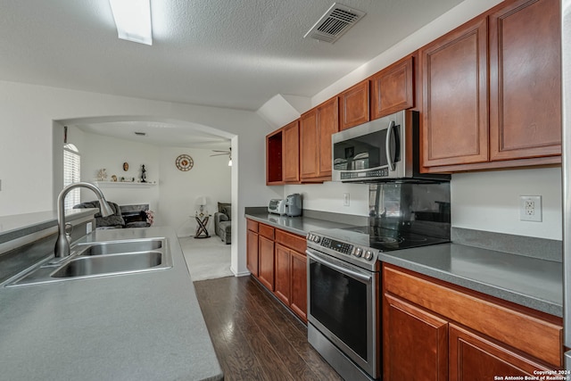 kitchen featuring ceiling fan, sink, dark hardwood / wood-style floors, a textured ceiling, and appliances with stainless steel finishes