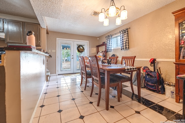 dining area with french doors, light tile patterned floors, a chandelier, and a textured ceiling