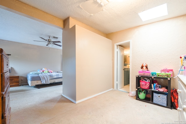 rec room featuring light carpet, a textured ceiling, a skylight, and ceiling fan