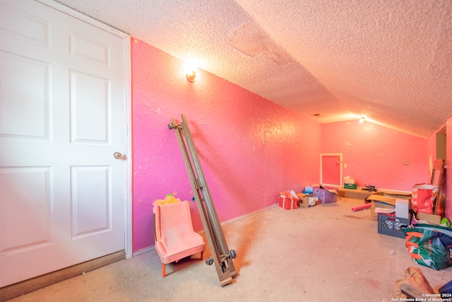 recreation room with a textured ceiling and vaulted ceiling