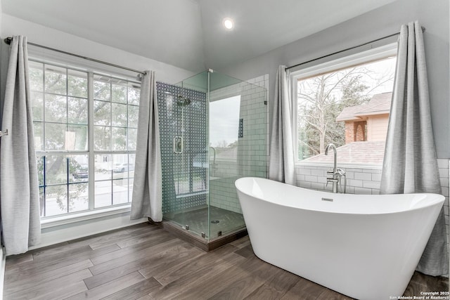 full bathroom with a shower stall, a freestanding bath, a wealth of natural light, and wood finished floors