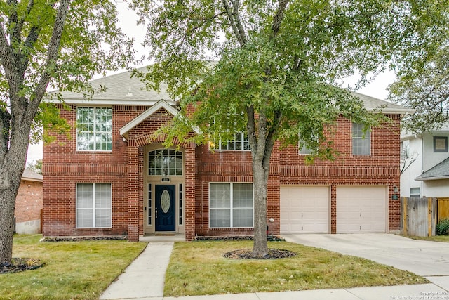 traditional-style home featuring a garage, brick siding, fence, driveway, and a front yard