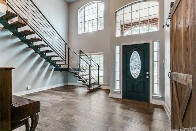 foyer entrance with wood finished floors, a high ceiling, baseboards, and a barn door