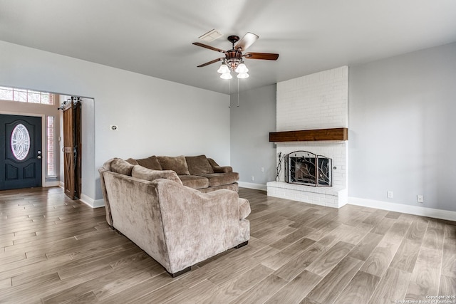 living room with ceiling fan, a fireplace, baseboards, and wood finished floors