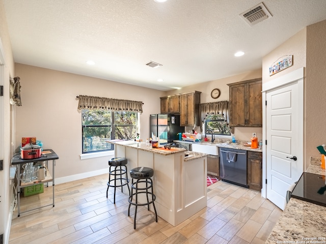 kitchen featuring black refrigerator, dishwasher, a kitchen island, and plenty of natural light