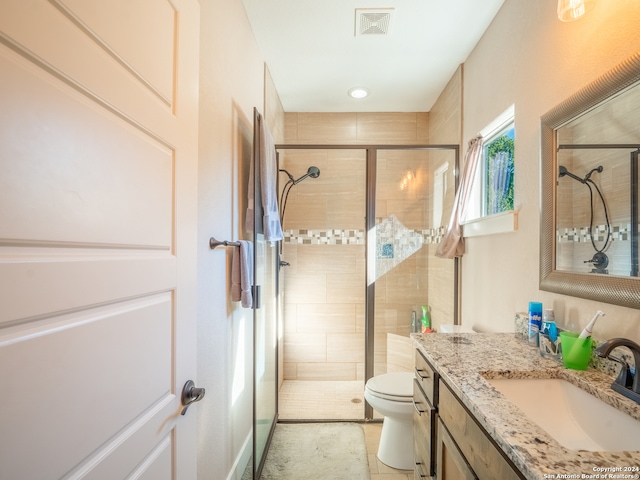 bathroom with tile patterned floors, vanity, a shower with shower door, and toilet