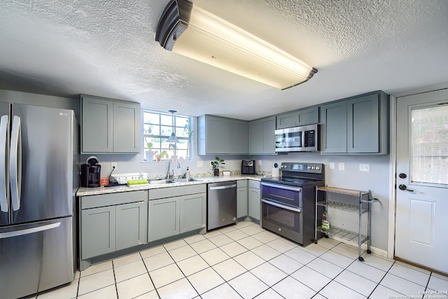 kitchen with appliances with stainless steel finishes, a textured ceiling, and gray cabinetry