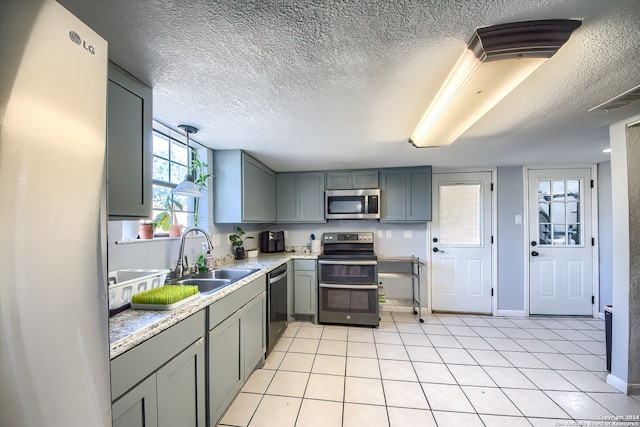 kitchen with sink, light tile patterned floors, stainless steel appliances, and a textured ceiling