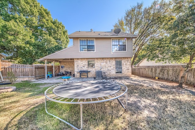 back of property with a patio, a trampoline, central AC, and a lawn