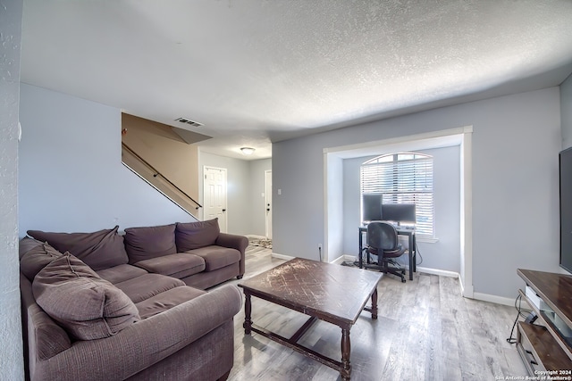 living room with a textured ceiling and light wood-type flooring