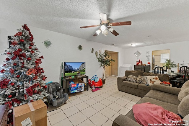 tiled living room with ceiling fan, washing machine and clothes dryer, and a textured ceiling