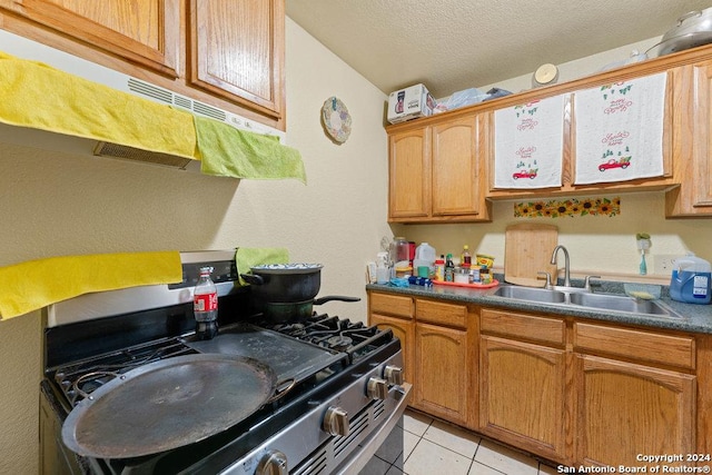 kitchen with sink, gas stove, a textured ceiling, and light tile patterned flooring