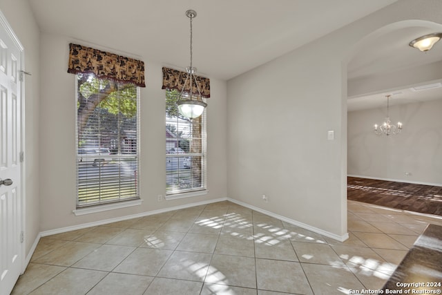 unfurnished dining area featuring light hardwood / wood-style floors and an inviting chandelier