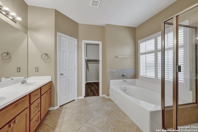 bathroom with tile patterned floors, vanity, and tiled tub