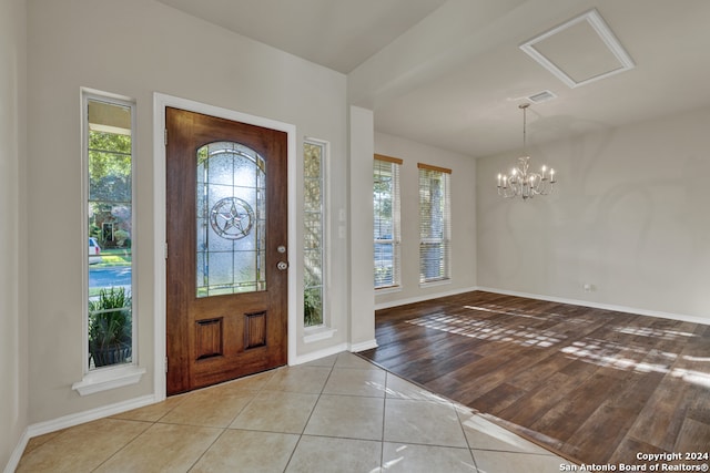 foyer featuring an inviting chandelier, a wealth of natural light, and light hardwood / wood-style flooring