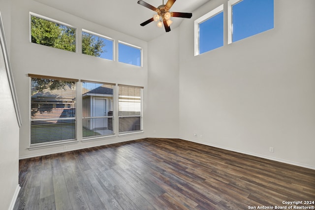 empty room featuring ceiling fan, dark hardwood / wood-style flooring, high vaulted ceiling, and a healthy amount of sunlight