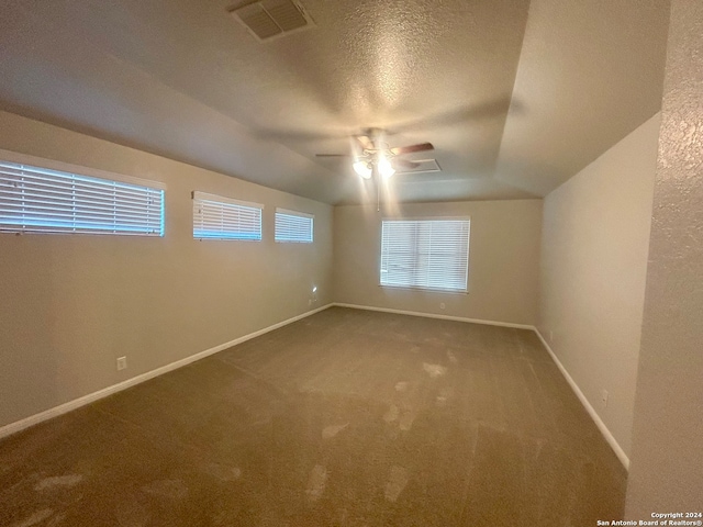 carpeted spare room featuring ceiling fan, a textured ceiling, and vaulted ceiling