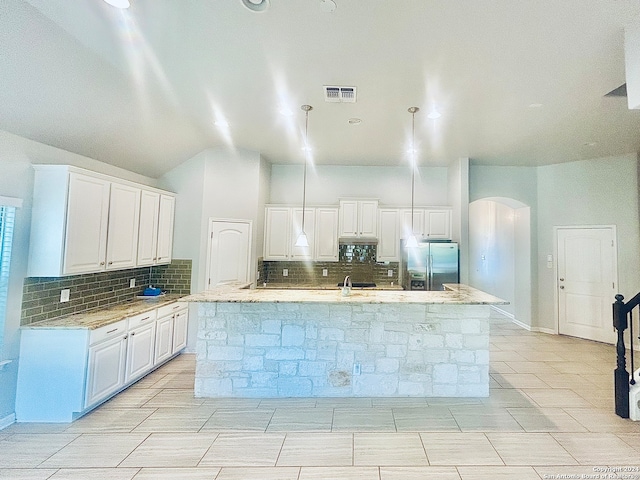 kitchen featuring white cabinetry, decorative backsplash, stainless steel fridge with ice dispenser, and a center island with sink