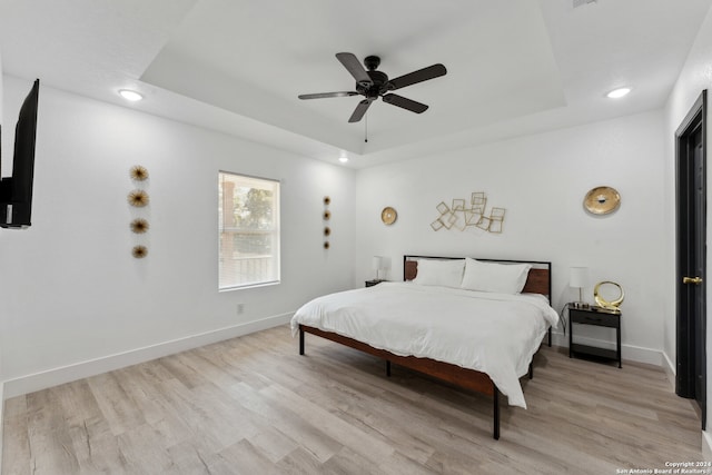 bedroom with a tray ceiling, light hardwood / wood-style flooring, and ceiling fan