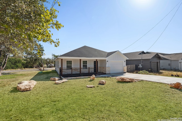 view of front of home with covered porch, a garage, and a front lawn