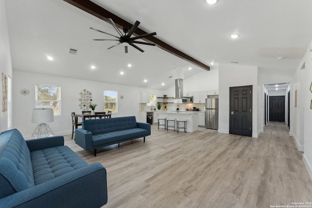 living room with light wood-type flooring, lofted ceiling with beams, ceiling fan, and sink