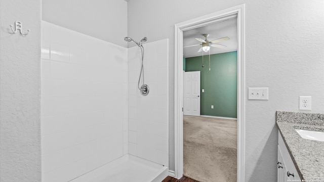 bathroom with vanity, ceiling fan, and tiled shower