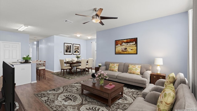 living room with ceiling fan and dark wood-type flooring