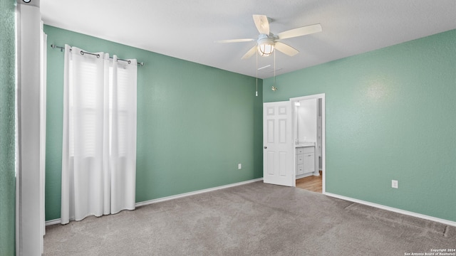 unfurnished bedroom featuring ceiling fan, light colored carpet, and ensuite bath