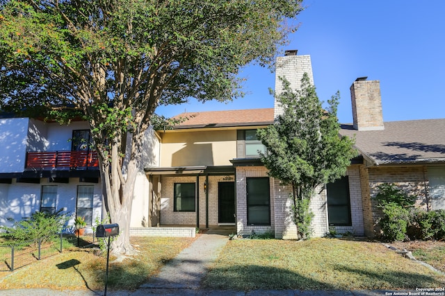 view of front of house featuring a balcony and a front yard