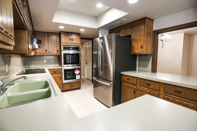 kitchen with light tile patterned flooring, appliances with stainless steel finishes, a raised ceiling, and sink