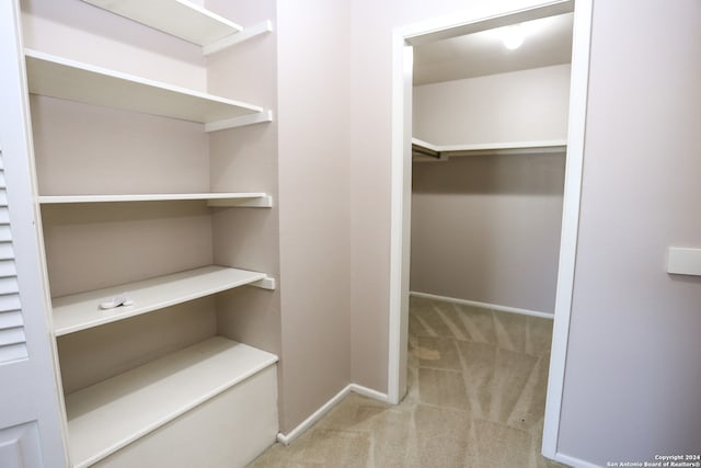 walk in closet featuring light colored carpet