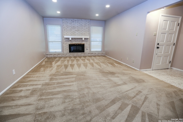 unfurnished living room featuring light carpet and a brick fireplace