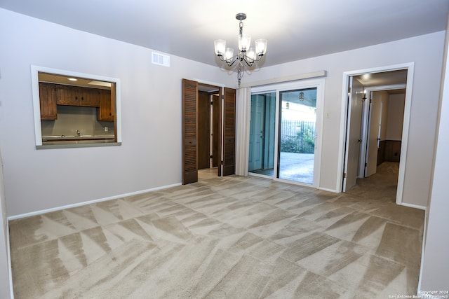 carpeted empty room featuring a chandelier and sink