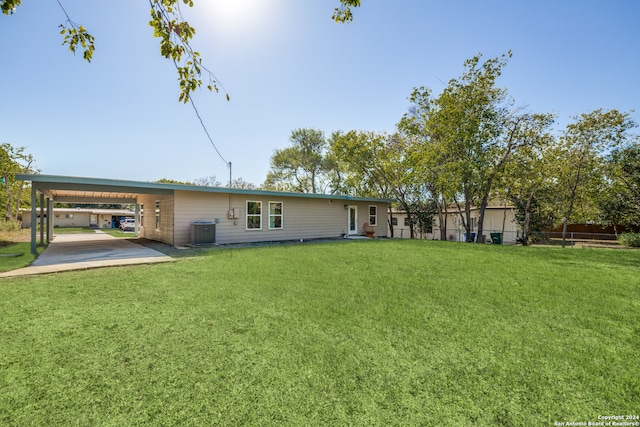 back of property featuring a yard, central AC unit, and a carport