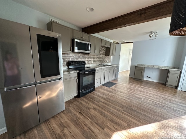 kitchen with gray cabinetry, beamed ceiling, backsplash, hardwood / wood-style floors, and appliances with stainless steel finishes