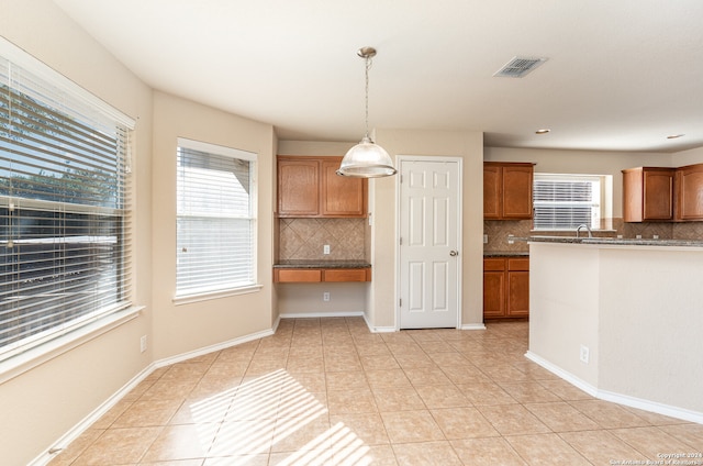 kitchen with light tile patterned flooring, hanging light fixtures, and tasteful backsplash